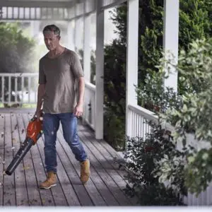 a man using a leaf blower to clear leaves from a veranda