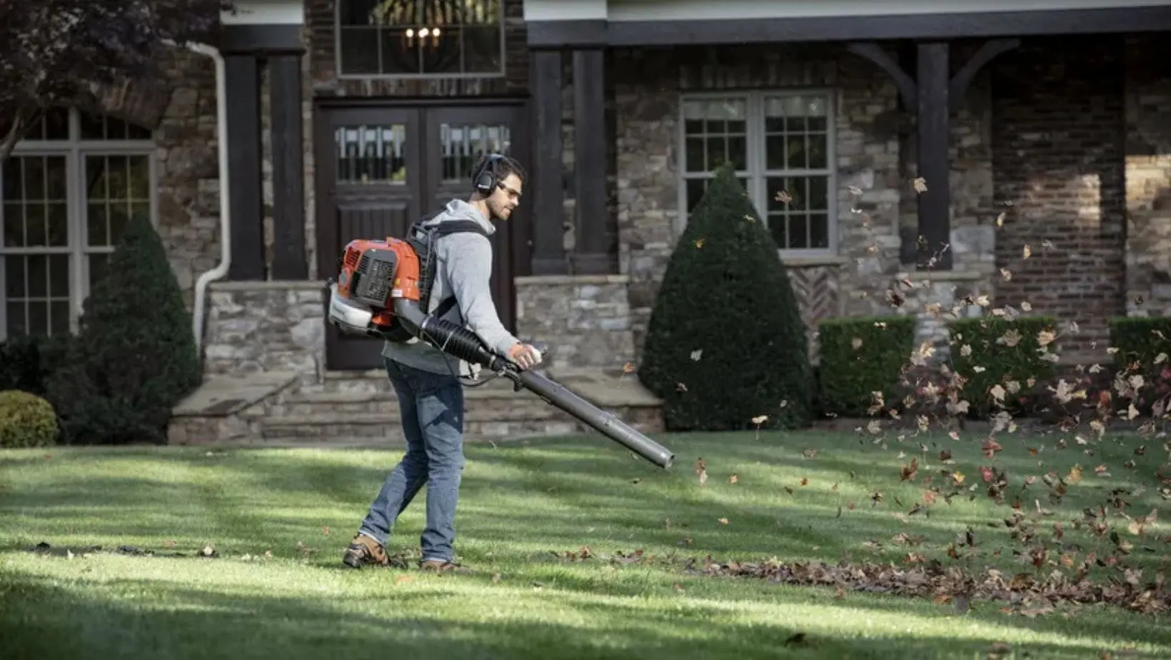 a man using a Husqvarna leaf blower in a garden