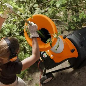 a woman feeding branches into the STIHL GHE 250 Electric Chipper Shredder