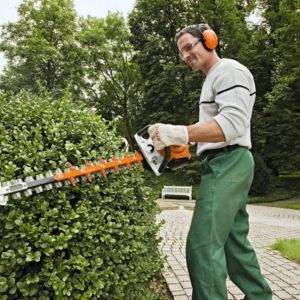 a man using a petrol hedge trimmer