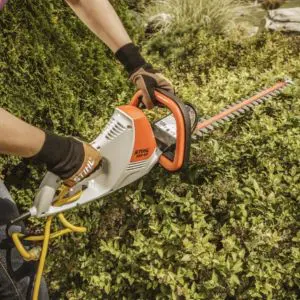 someone using an electric hedge trimmer