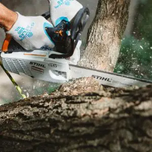 someone cutting a tree branch with a chainsaw
