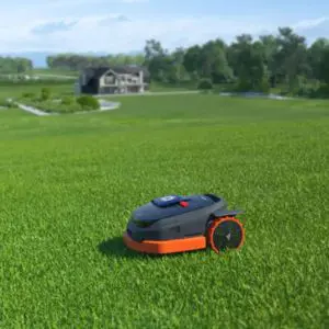 a Segway Navimow X390E Robotic Mower cutting a very large lawn, with a mansion in the background