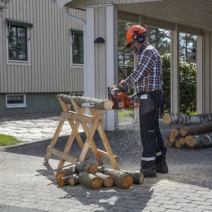 a man using a chainsaw to cut wood, which is positioned on a stand