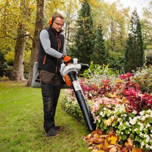 a man collecting fallen leaves from a garden, using a vacuum shredder
