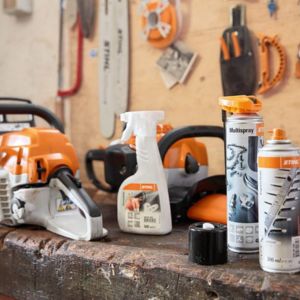 a chainsaw and a variety of chainsaw cleaning solutions on a bench