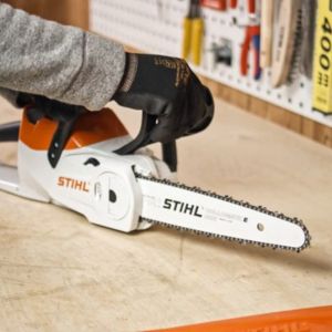 someone putting a chainsaw on a bench to carry out maintenance