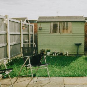 a green shed, fence and 2 garden chairs