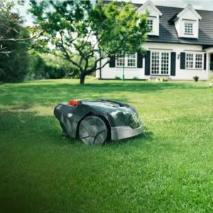 the Husqvarna 105 Automower on a lawn, with a large house and tree in the background