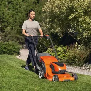 a woman mowing a lawn using the Husqvarna LC 247i Cordless Lawnmower