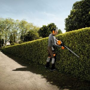 a man cutting the side of a hedge using the STIHL HS 87 Petrol Hedge Trimmer