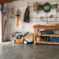 a lawnmower and other essential garden tools and machines in a garage