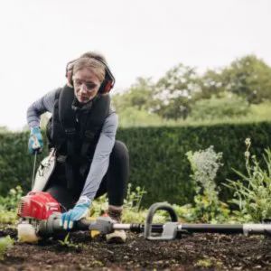 a woman wearing ear defenders, checking a multi tool