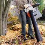 someone clearing leaves using a vacuum shredder garden tool