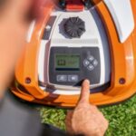 a man programming an orange STIHL robotic mower