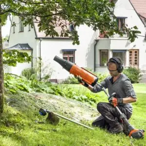a man sat on grass, assembling a Husqvarna multi tool
