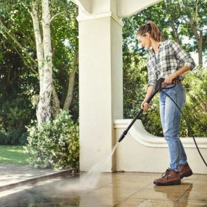 a woman cleaning a patio with a pressure washer