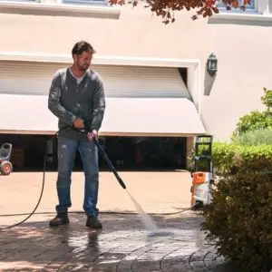 a man using the STIHL RE 90 to clean a driveway