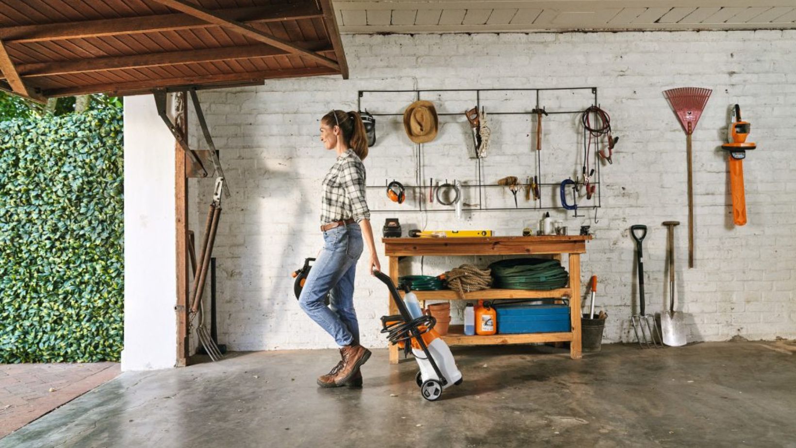 a woman taking a pressure washer out of a garage