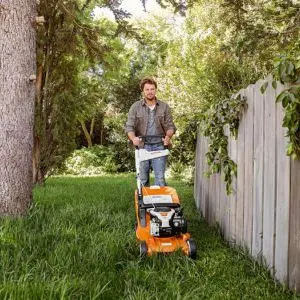 a man mowing a lawn near a fence