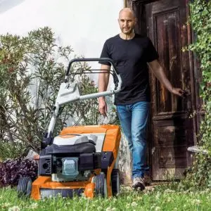 a man coming out of his house, looking at a mulching mower