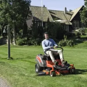 a man using a ride-on mower to mow a lawn