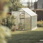 a greenhouse in a garden, with its door and vent open
