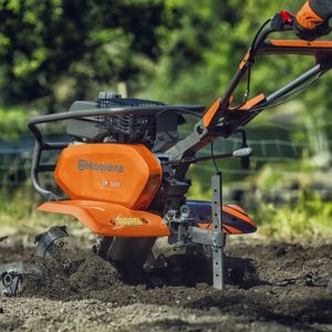 a close up of an orange Husqvarna rotavator tilling soil