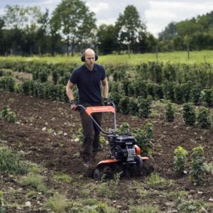 a man using a tiller rotavator to prepare soil in a field