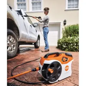 a woman using the STIHL REA 60 PLUS Cordless Pressure Washer to clean the outside of a white vehicle