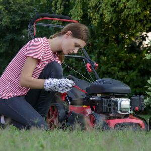 a woman checking the oil level on a petrol lawnmower