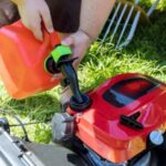 someone putting fresh fuel in a red petrol lawnmower