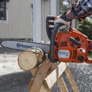 a man using the Husqvarna 120 II Petrol Chainsaw to cut a log that is positioned on a wooden stand