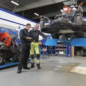 2 men in a garden machinery workshop looking at information on a clipboard