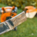 a close up of a lawnmower blade, with the mower in the background