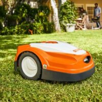 an orange and white STIHL iMow robotic lawn mower in a garden