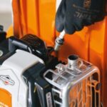 someone changing a petrol lawnmower's spark plug 