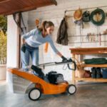 a woman storing a petrol mower in a white-walled garage