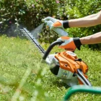 someone spraying a STIHL hedge cutter's blade with a cleaning solution
