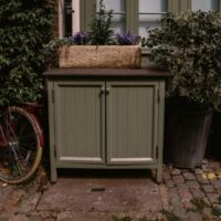 a green wooden cupboard repurposed as garden storage