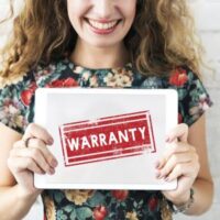 a woman holding up a sign that reads 'warranty'