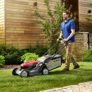 a man mowing a lawn with a red Honda lawnmower