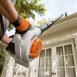 someone using a STIHL blower and gutter cleaning set to clean a house's first-story guttering