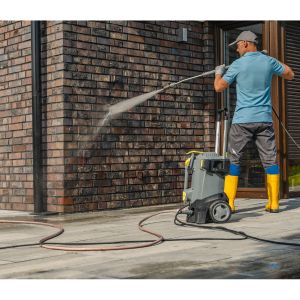 a man cleaning a house's exterior brick wall using a pressure washer
