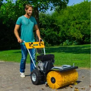 a man wearing a turquoise t-shirt, pushing the STIGA SWS 800 G Self-Propelled Sweeper along a path in a park