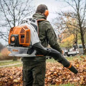 a man blowing fallen leaves in a park, using the STIHL BR 800 C-E Petrol Backpack Leaf Blower