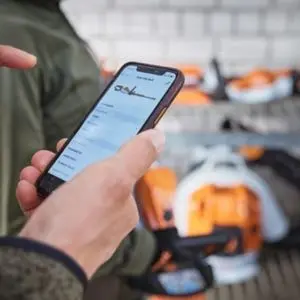 a man in a workshop using the STIHL Connected app on his smartphone