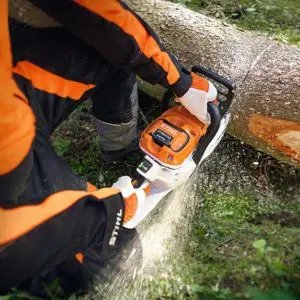 a close up of someone dressed in orange and black PPE, using the STIHL MSA 300 Cordless Chainsaw to cut a log