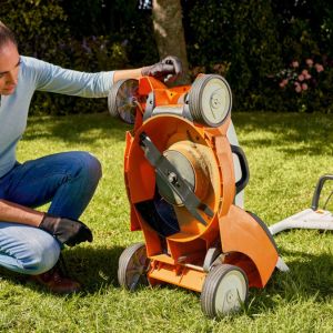 a woman examining the underside of a STIHL lawnmower