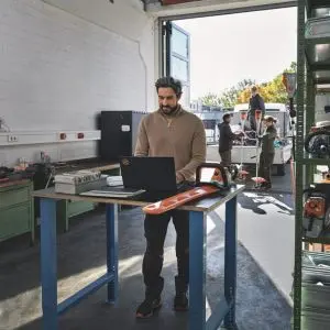 a man in a workshop using the STIHL Connect Pro portal on a laptop